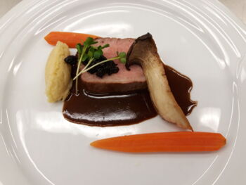 Zartes Fleisch mit dunkler Sauce und Möhren und Pilzen.