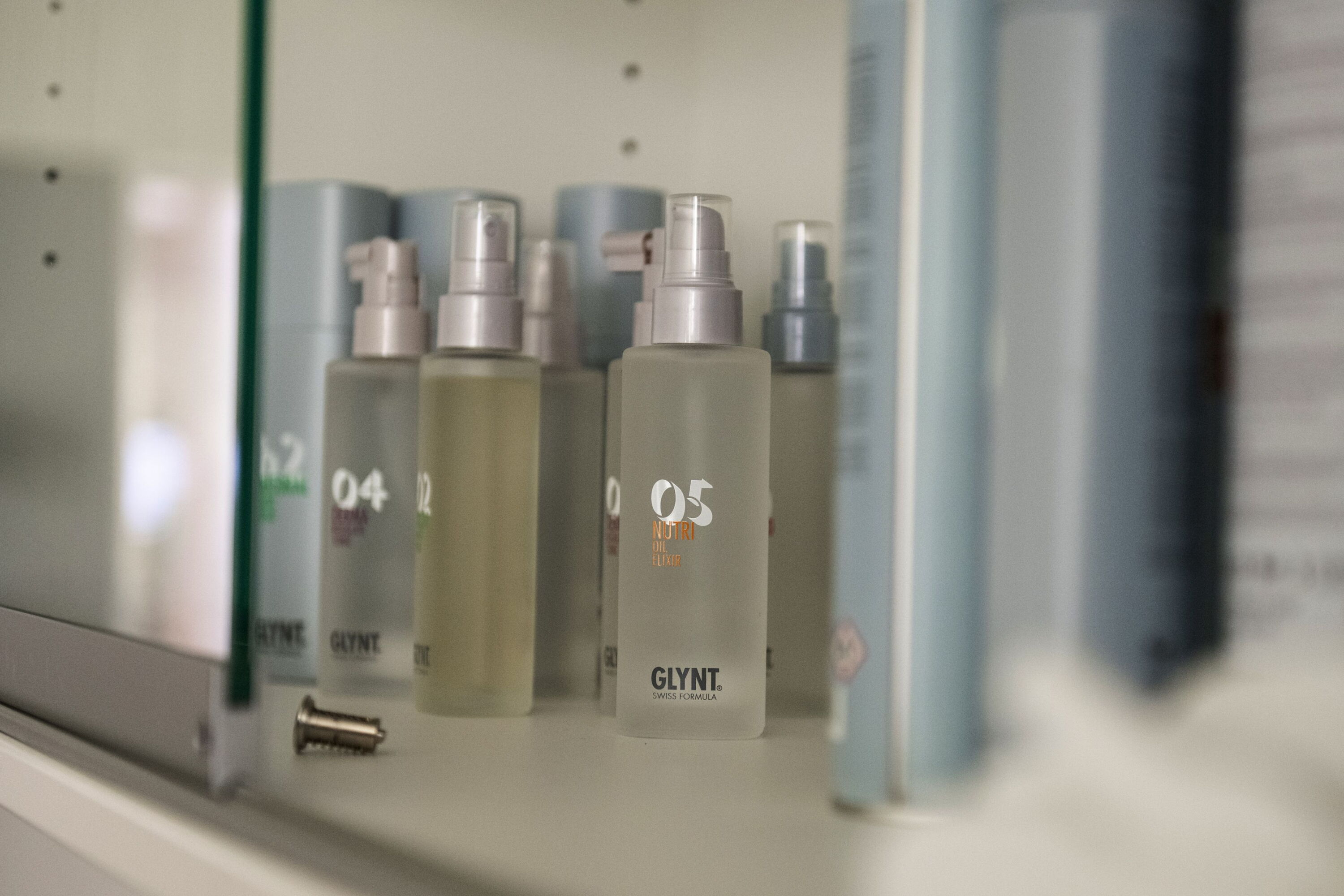 In einem Schrank stehen edel anmutende Glassprühflaschen der Marke O5 Glynt.