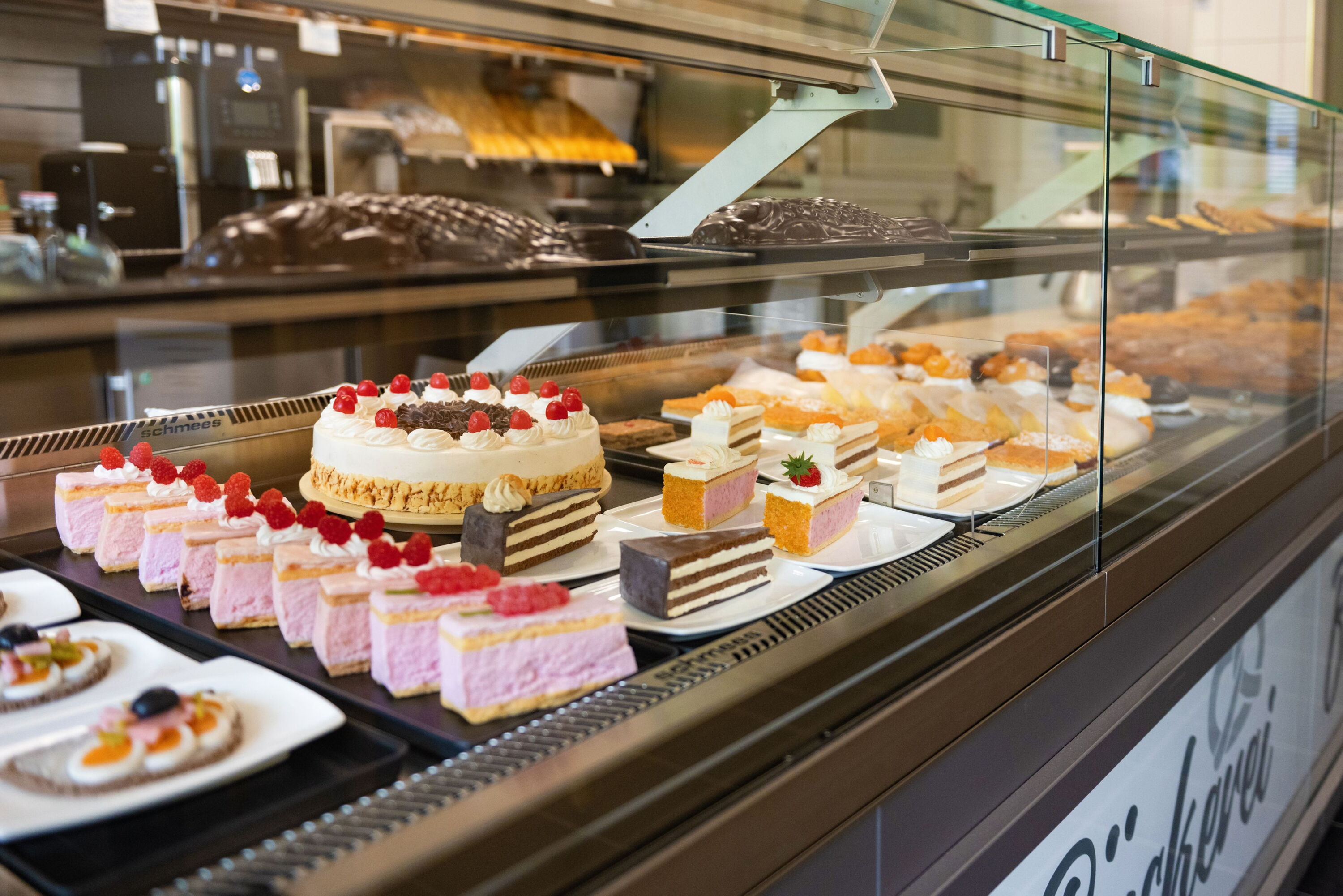 Verkaufstheke mit Torten, Kuchenstücken und Broten hinter Glas.